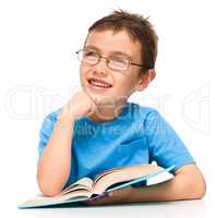 Young boy is daydreaming while reading book