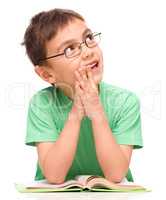 Young boy is daydreaming while reading book