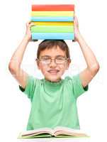 Little boy is holding a pile of books
