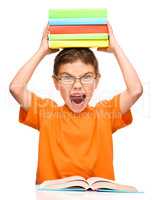 Little boy is holding a pile of books