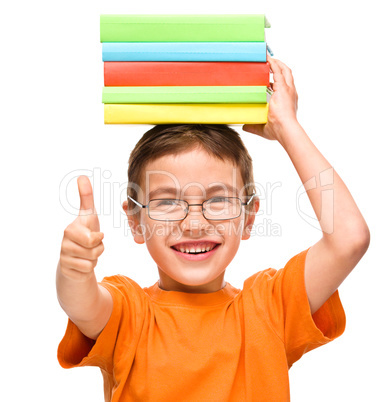 Little boy is holding a pile of books