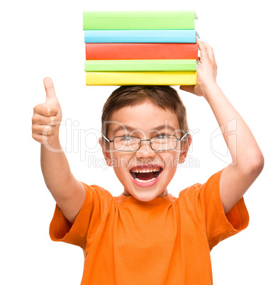 Little boy is holding a pile of books