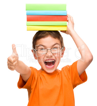 Little boy is holding a pile of books