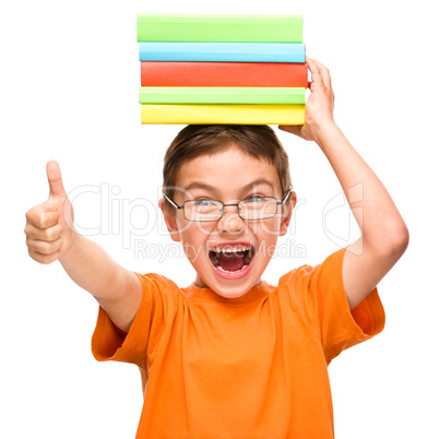 Little boy is holding a pile of books