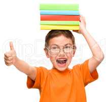Little boy is holding a pile of books