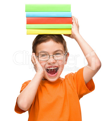 Little boy is holding a pile of books