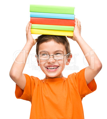 Little boy is holding a pile of books