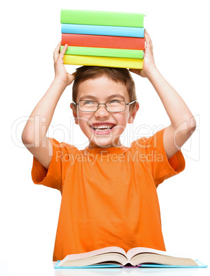 Little boy is holding a pile of books