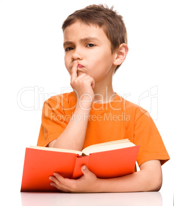 Young boy is daydreaming while reading book