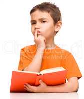 Young boy is daydreaming while reading book