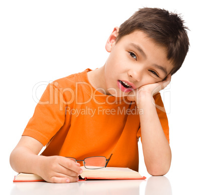 Little boy is tired to read his book