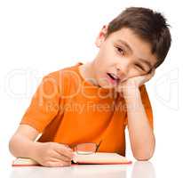 Little boy is tired to read his book