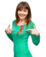 Woman is pointing to the red awareness ribbon