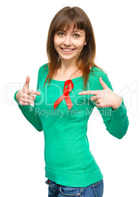 Woman is pointing to the red awareness ribbon