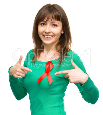 Woman is pointing to the red awareness ribbon