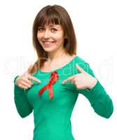 Woman is pointing to the red awareness ribbon