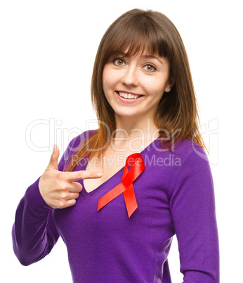 Woman is pointing to the red awareness ribbon