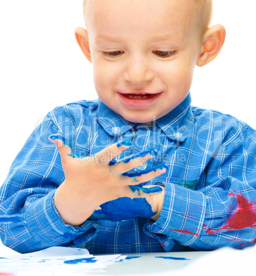 Little boy is playing with paints