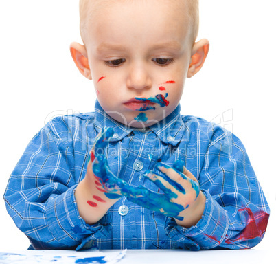 Little boy is playing with paints