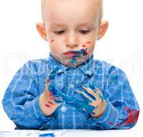 Little boy is playing with paints