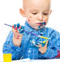 Little boy is playing with paints