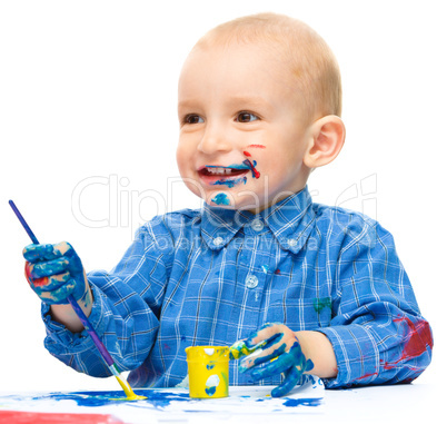 Little boy is playing with paints