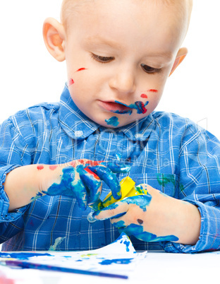 Little boy is playing with paints