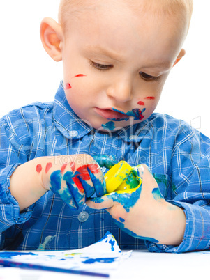 Little boy is playing with paints