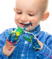 Little boy is playing with paints