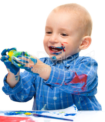 Little boy is playing with paints