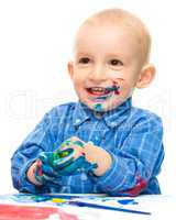 Little boy is playing with paints