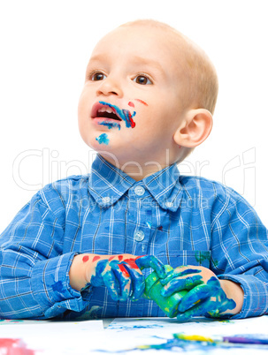 Little boy is playing with paints