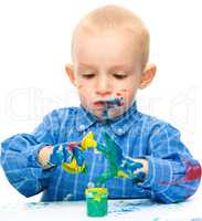 Little boy is playing with paints