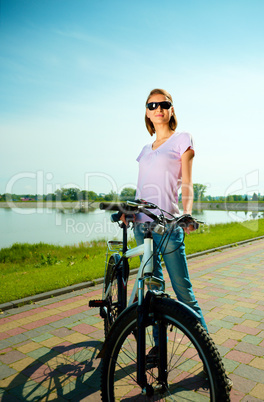 Young woman is standing behind bicycle