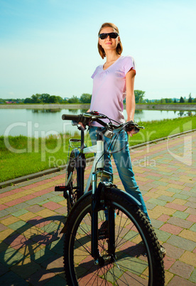 Young woman is standing behind bicycle