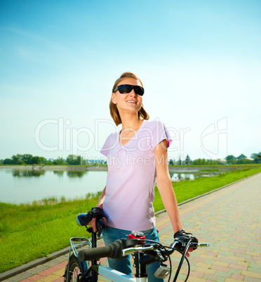 Young woman is standing behind bicycle