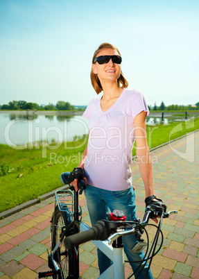 Young woman is standing behind bicycle