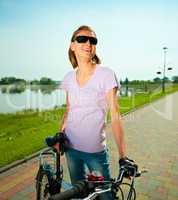 Young woman is standing behind bicycle