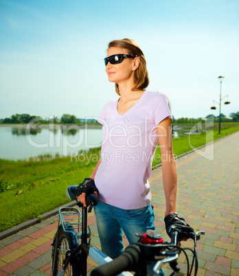 Young woman is standing behind bicycle