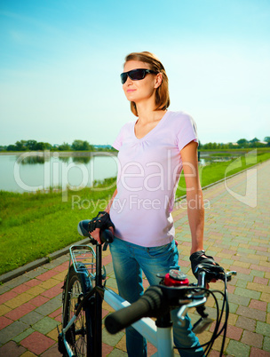 Young woman is standing behind bicycle