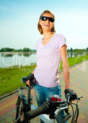 Young woman is standing behind bicycle