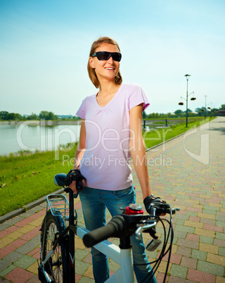 Young woman is standing behind bicycle