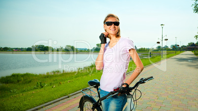 Young woman is standing behind bicycle