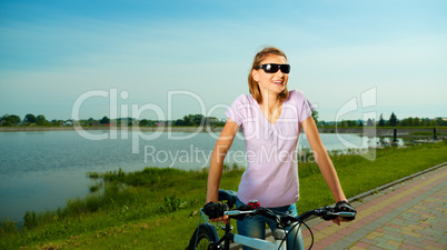 Young woman is standing behind bicycle