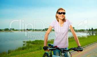 Young woman is standing behind bicycle