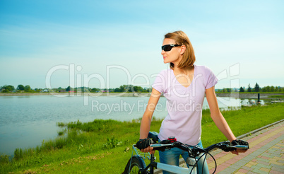 Young woman is standing behind bicycle