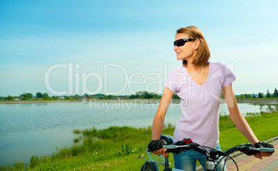 Young woman is standing behind bicycle