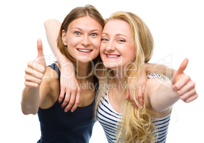 Two young happy women showing thumb up sign