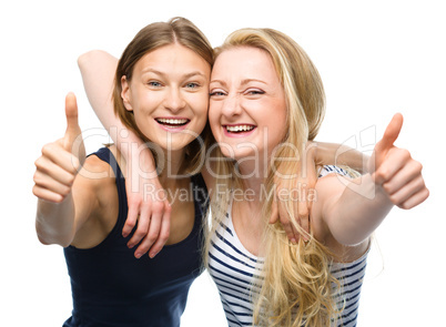 Two young happy women showing thumb up sign