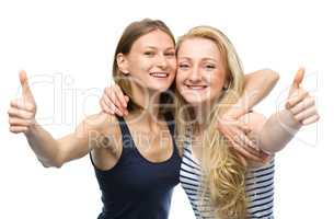 Two young happy women showing thumb up sign